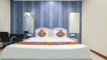 Una habitación de hotel con una cama grande, dos almohadas, un escritorio y una silla.