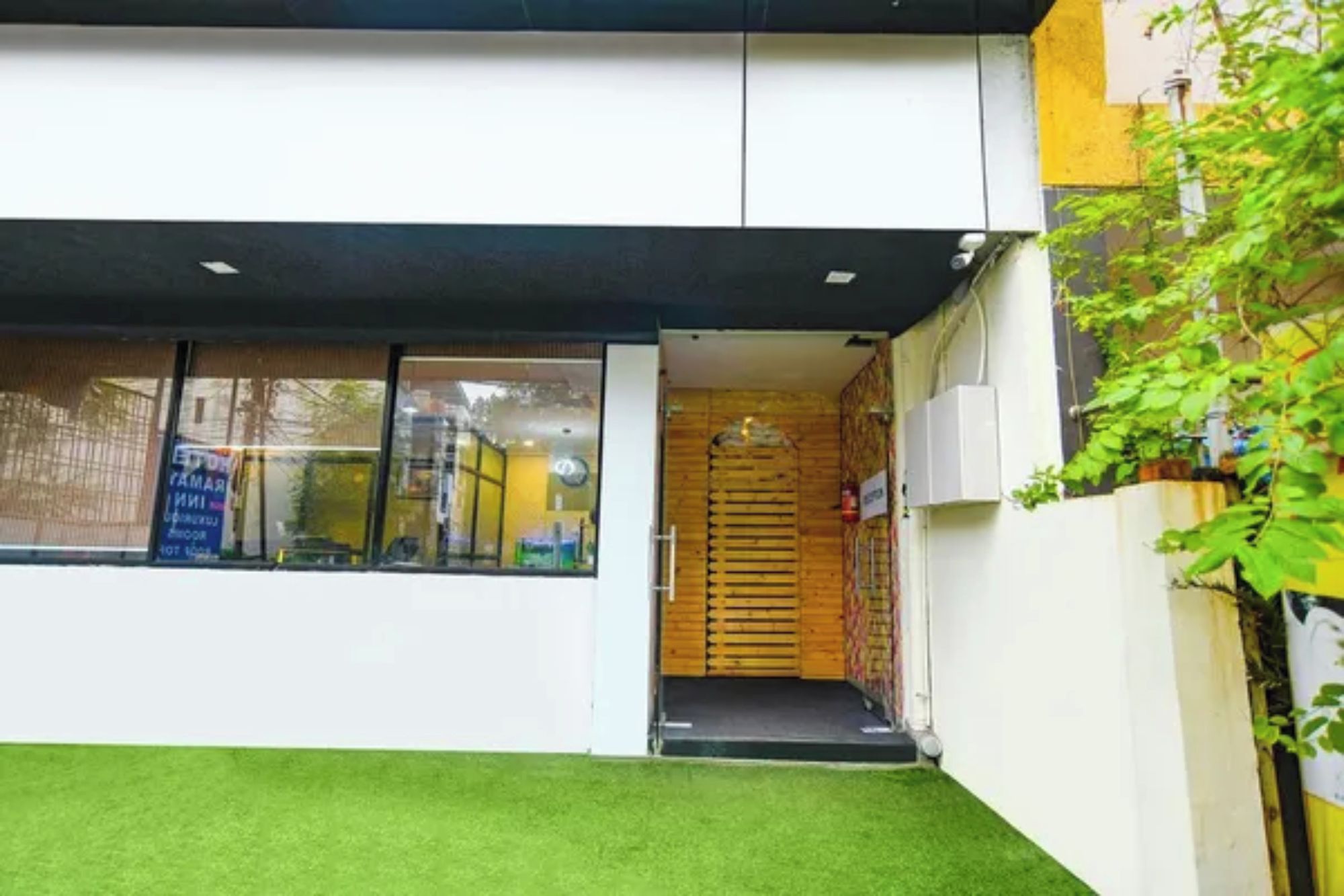 Un edificio moderno con techo plano, puerta de madera y un pequeño acceso.