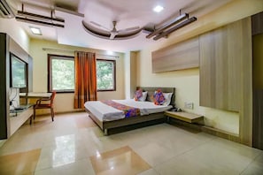 A bedroom with a bed, a desk, a chair, a window with curtains, and a ceiling fan. - FabHotel Maanpreet (Bhopal)