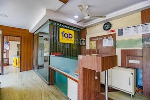 A hotel reception area with a check-out counter, a clock, and a sign indicating check-out time. - FabHotel Maanpreet (Bhopal)