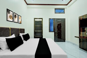 Une chambre d’hôtel avec un lit, une armoire, une salle de bain avec une porte en verre et une petite fenêtre.