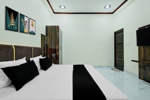 Un dormitorio con cama, armario, televisión y obras de arte en la pared.