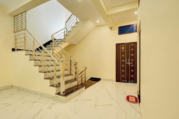 Una escalera con barandillas metálicas y escalones de mármol que conduce a un piso superior.