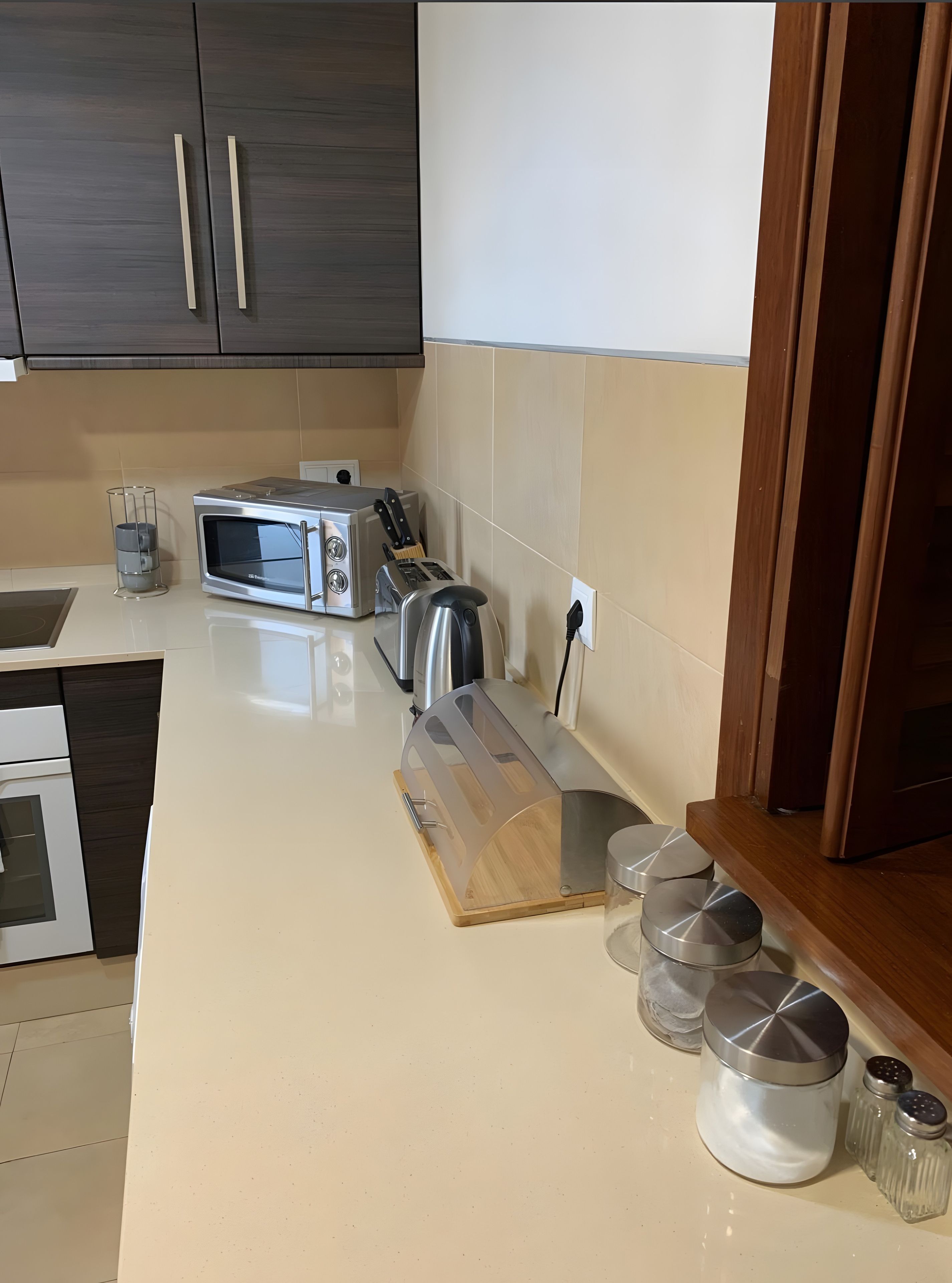 A modern kitchen with a microwave, toaster, and wooden cutting board.