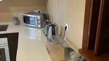 A modern kitchen with a microwave, toaster, and wooden cutting board.