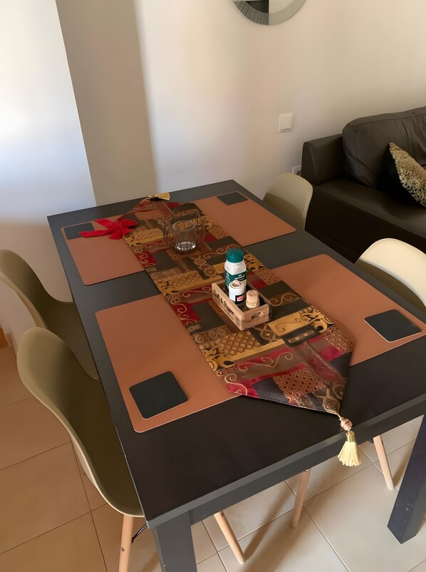 Un tavolo da pranzo con un runner decorativo, una bottiglia di sapone per le mani e una piccola scatola di legno.