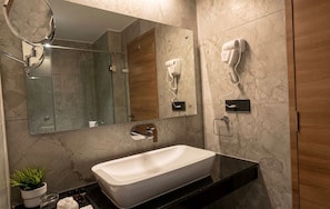 A modern bathroom with a large mirror, a white sink, and a hairdryer mounted on the wall. - Samasth Legacy  (Mysore)