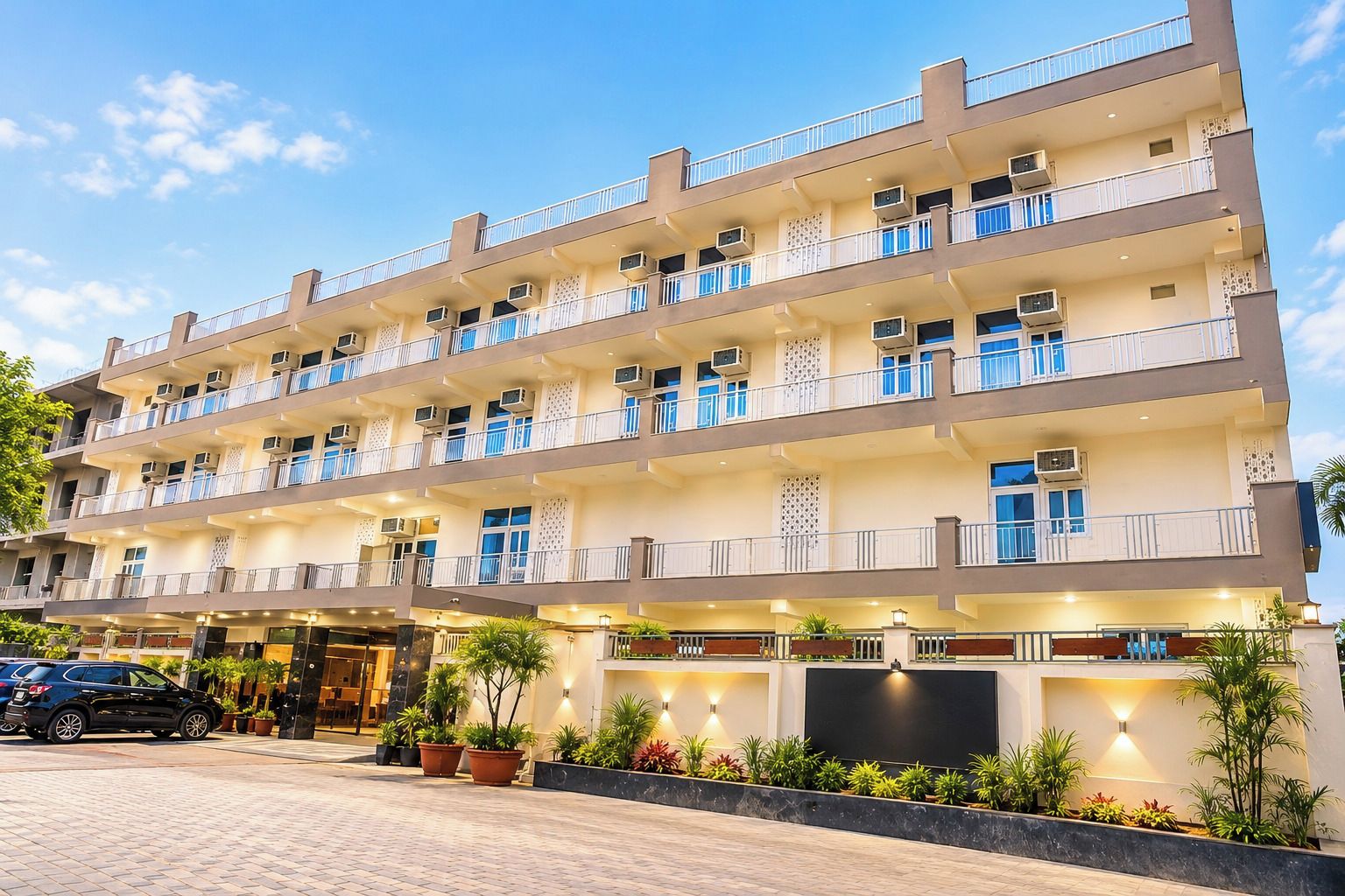 Un hôtel à plusieurs étages doté de balcons, de climatiseurs et d’un éclairage extérieur.