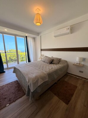A bedroom with a large bed, a ceiling light, an air conditioning unit, and a view through a sliding glass door. - New Listing (Nueva Esparta)