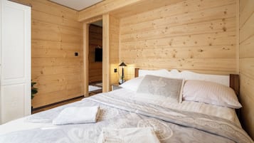 A wooden-paneled bedroom with a bed, pillows, and a nightstand.