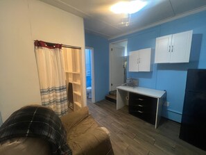 Una habitación con una cama, un escritorio y un armario. Hay una puerta que conduce a otra habitación.