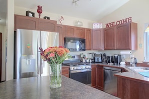 A kitchen with wooden cabinets, a refrigerator, a microwave, a stove, and a coffee maker.