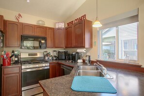 A kitchen with wooden cabinets, stainless steel appliances, a built-in oven, and a large window.