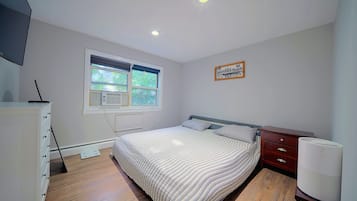 Un dormitorio con cama, cómoda, ventana y radiador.