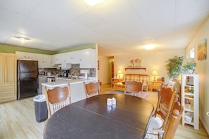 A spacious living area with a dining table surrounded by chairs, a kitchen with modern appliances, and a cozy seating area with a fireplace.