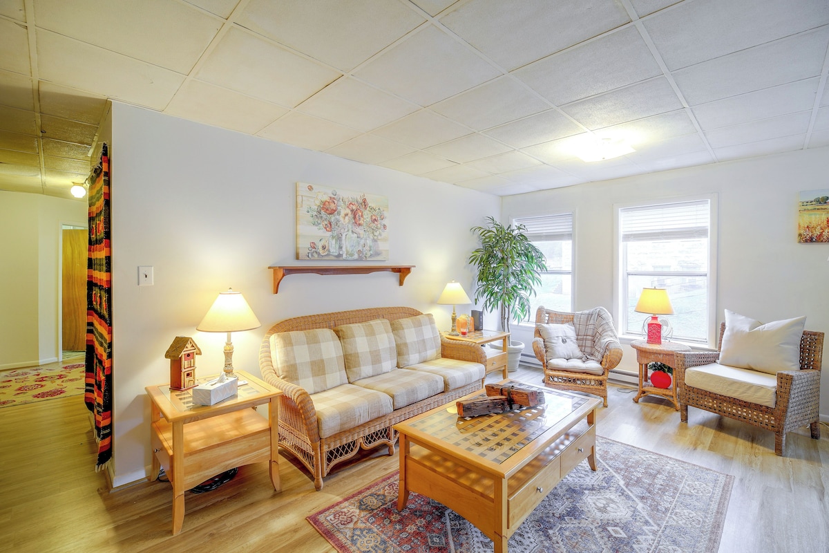 A living room with a sofa, two chairs, a coffee table, a lamp, a plant, and a painting on the wall.