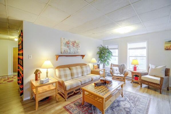 A living room with a sofa, two chairs, a coffee table, a lamp, a plant, and a painting on the wall.