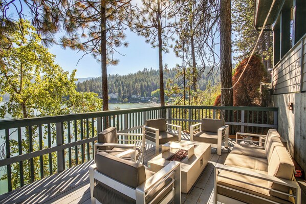 Una terraza con mobiliario exterior, con vista a un lago y un bosque.