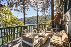 A deck with outdoor furniture overlooking a lake and forest.