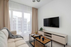 Ein modernes Wohnzimmer mit einer Couch, einem Couchtisch und einem an der Wand befestigten Flachbildfernseher.
