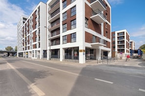 Ein mehrstöckiges Wohngebäude mit Balkonen, einem Fußgängereingang und blauem Himmel.