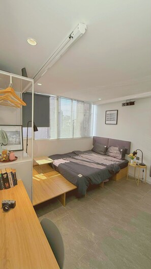 Une chambre à coucher moderne avec un lit, une table de chevet et un bureau avec une chaise.