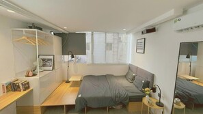 Une chambre à coucher moderne comprenant un lit, des tables de chevet, une armoire, une fenêtre avec des stores et un miroir.