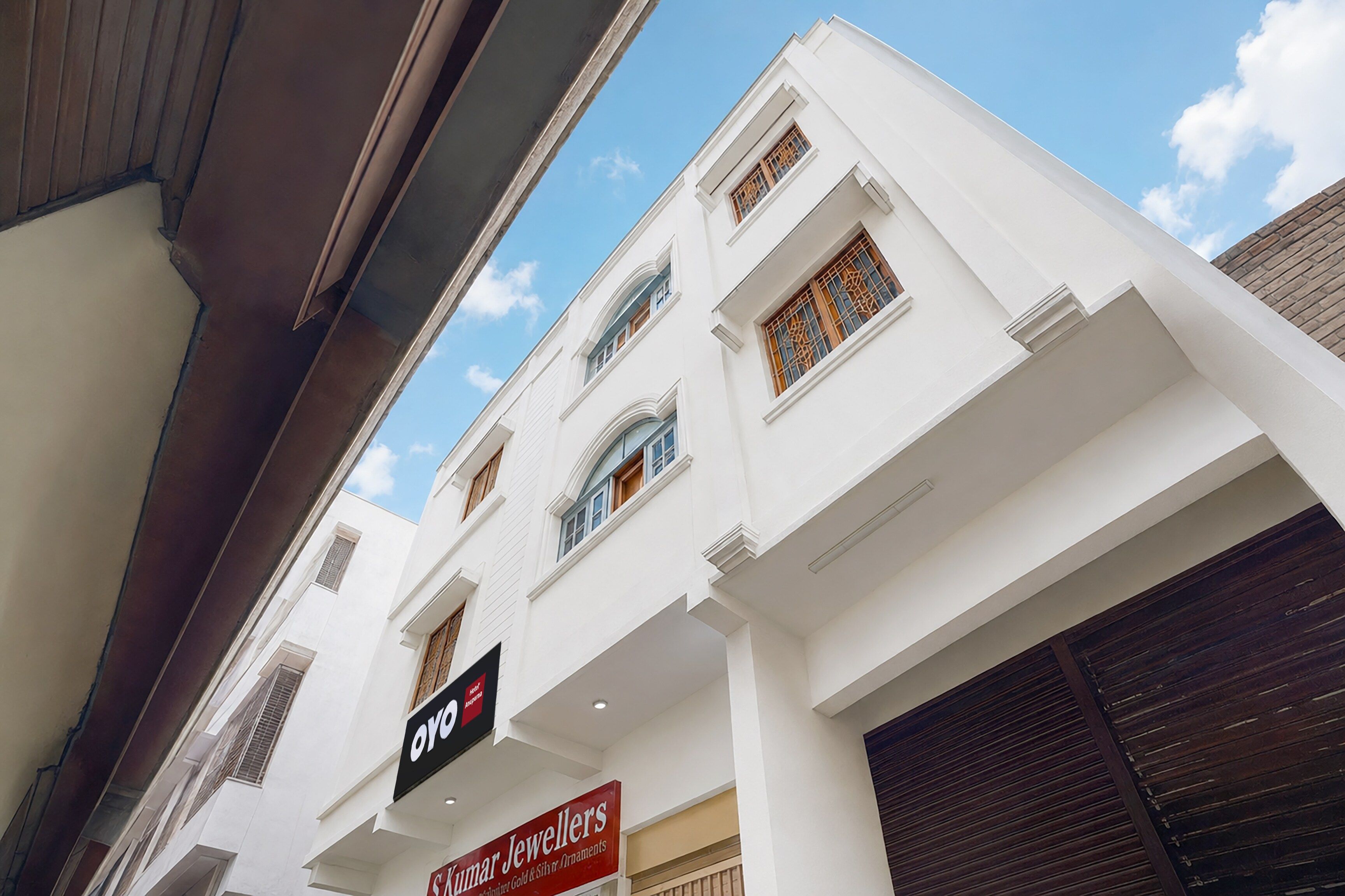 A multi-story building with a white facade, a sign for 'Kumar Jewellers,' and a partially visible storefront.