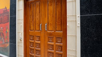A double wooden door with a handle and a lock, set in a building with a black and yellow wall.