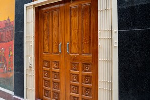 A double wooden door with a handle and a lock, set in a building with a black and yellow wall. - Hotel O Anupurna hotel (Lucknow)