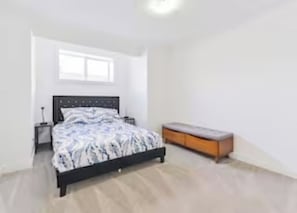 A bedroom with a bed, a nightstand, a bench, and a window. - Roku TV, 10 mins to Airport, Charming Suite (Calgary)