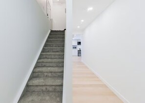 A staircase leading to a kitchen area with white walls and a wooden floor. - Roku TV, 10 mins to Airport, Charming Suite (Calgary)