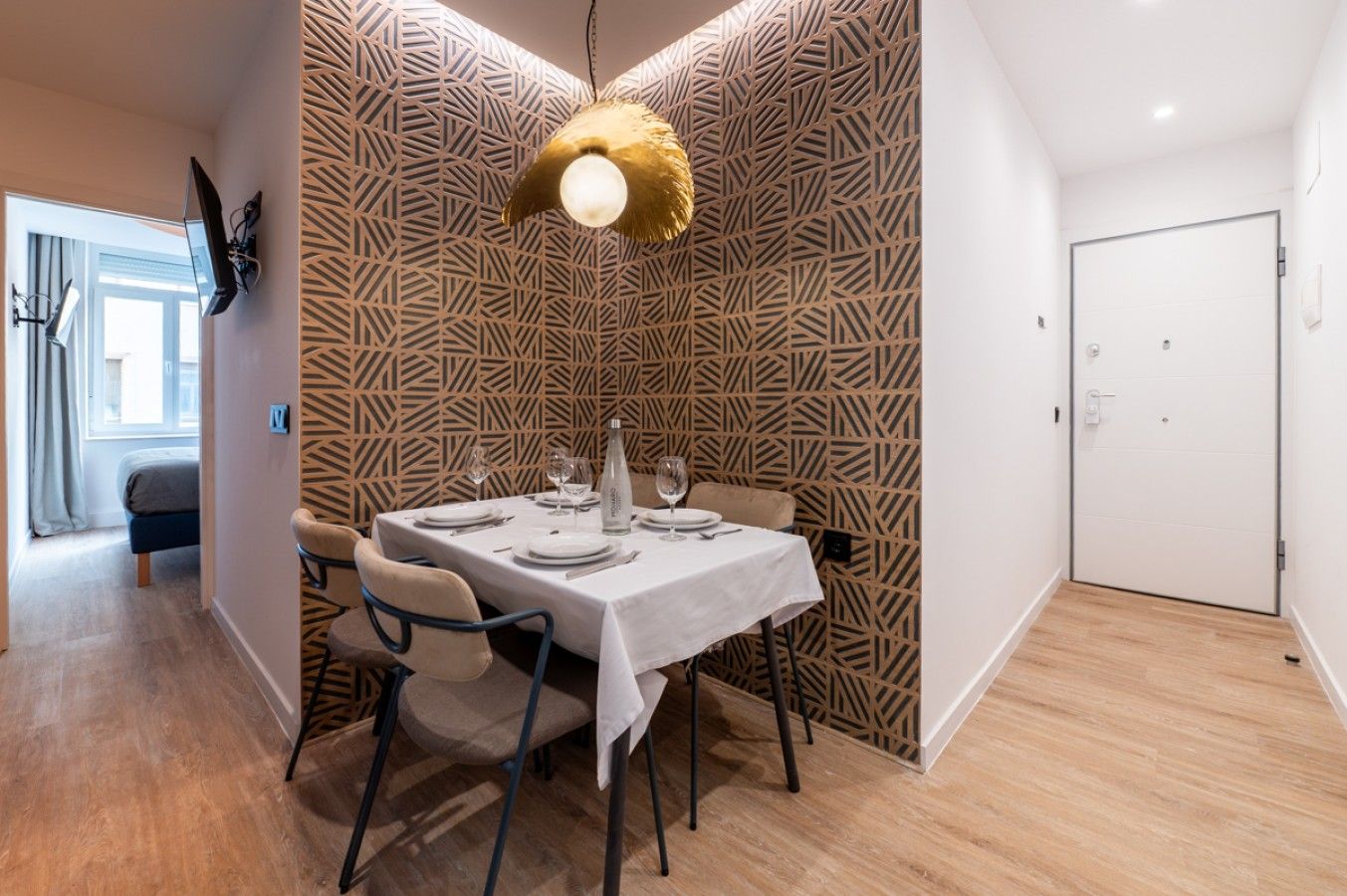 A dining area with a table set for four, a patterned wall, and a hanging light fixture.
