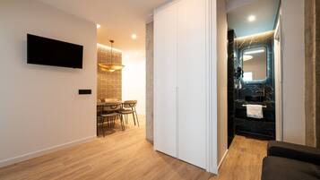 Een modern interieur met een eethoek, een wandtelevisie en een badkamer met een marmeren aanrechtblad en een grote spiegel.