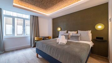 A modern hotel room with a large bed, a small side table, a wall-mounted light, and a window with curtains.