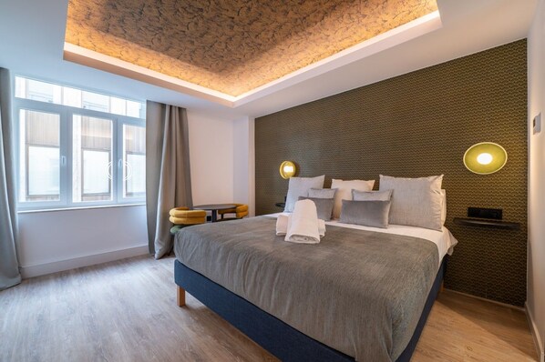 A modern hotel room with a large bed, a small side table, a wall-mounted light, and a window with curtains. - A33 Signature Residences - Sol by Monaro * * * * * (Madrid)