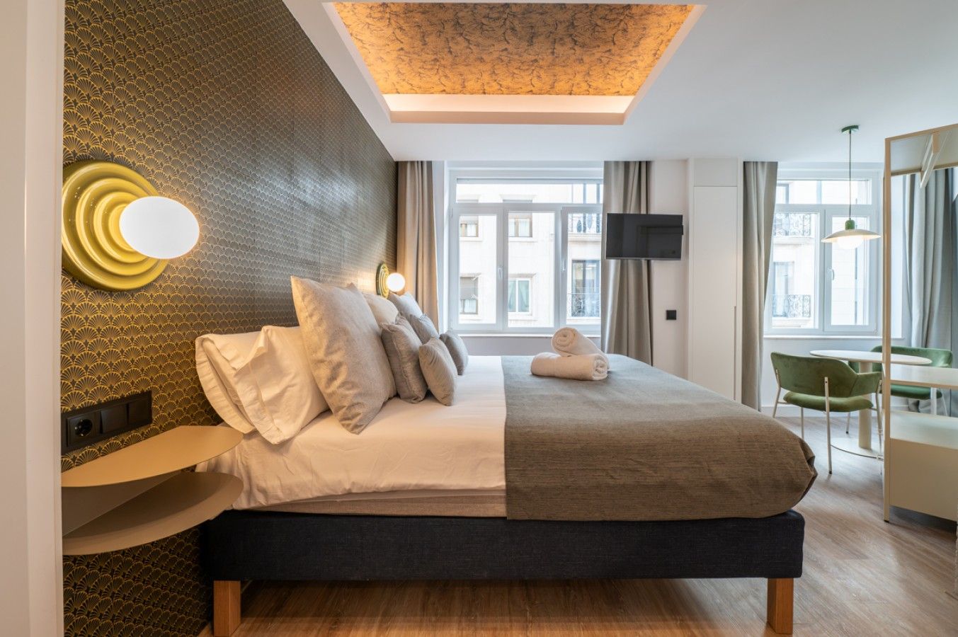 A modern hotel room with a bed, a desk, and a television.