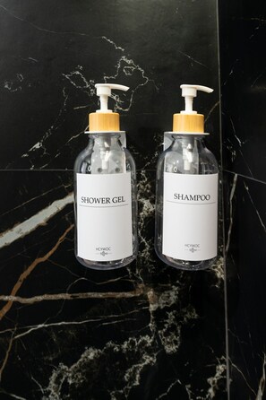 Two bottles of HCYWOC shower gel and shampoo on a black marble surface. - A33 Signature Residences - Sol von Monaro * * * * * (Madrid)