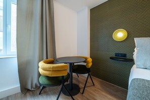 A hotel room with a round table, two chairs, a bed, a wall-mounted light, and a window with curtains. - A33 Signature Residences - Sol von Monaro * * * * * (Madrid)