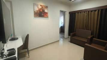 A living room with a flat-screen TV, a sofa, a chair, and a painting on the wall.