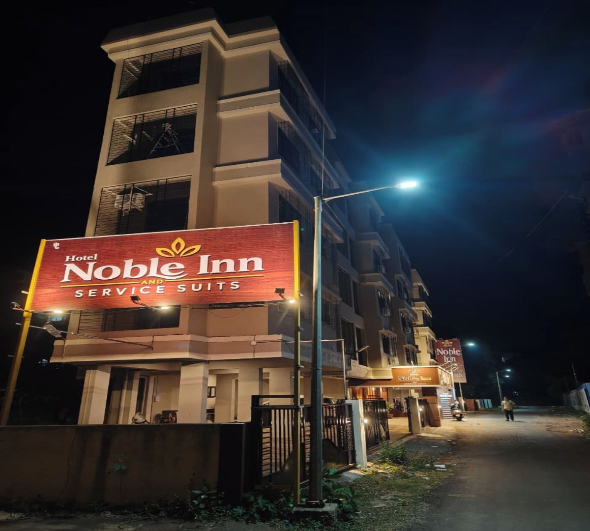 Un immeuble à plusieurs étages, sur lequel on peut voir une enseigne bien visible indiquant « Hotel Noble Inn Service Suites ».