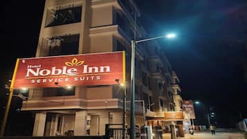 Un immeuble à plusieurs étages, sur lequel on peut voir une enseigne bien visible indiquant « Hotel Noble Inn Service Suites ».