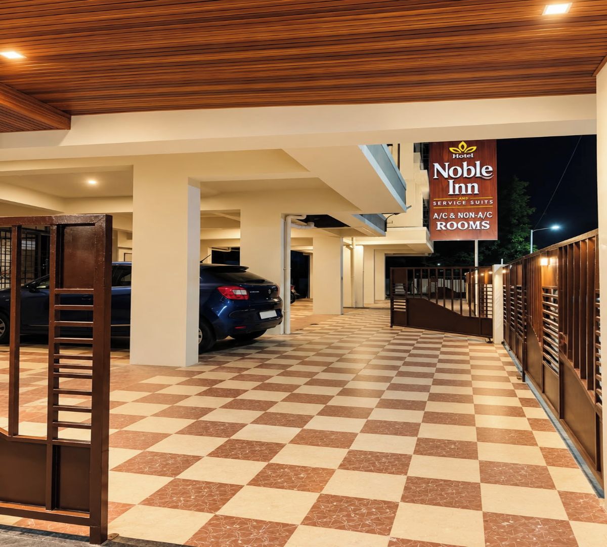 Entrada de hotel con piso de cuadros, un coche estacionado y un cartel que indica habitaciones de servicio.