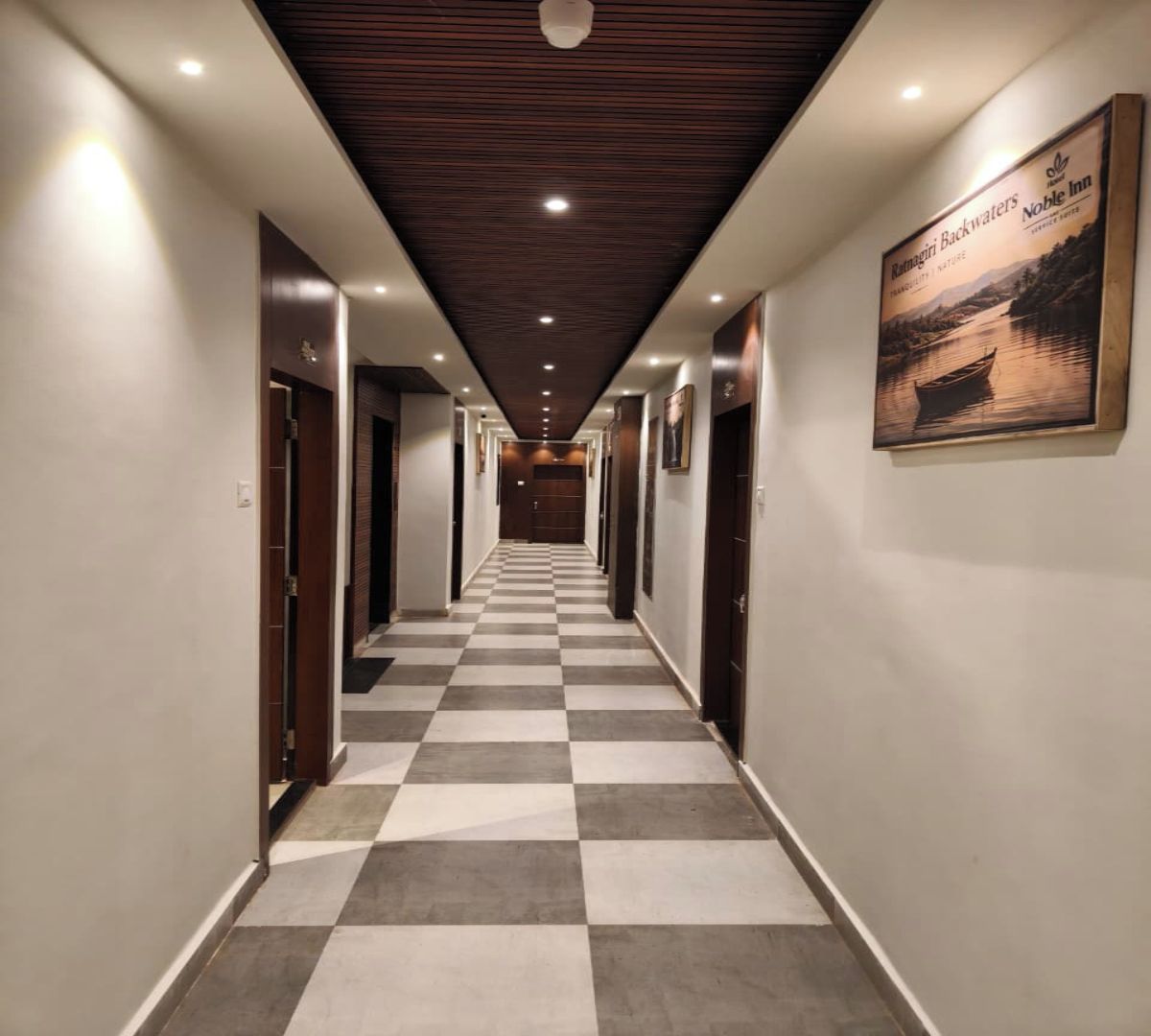 Un pasillo de hotel con piso de cuadros, techo de paneles de madera y cuadros en las paredes.