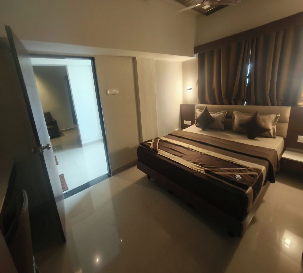 Une chambre à coucher moderne avec un lit, une valise, une armoire et un miroir.