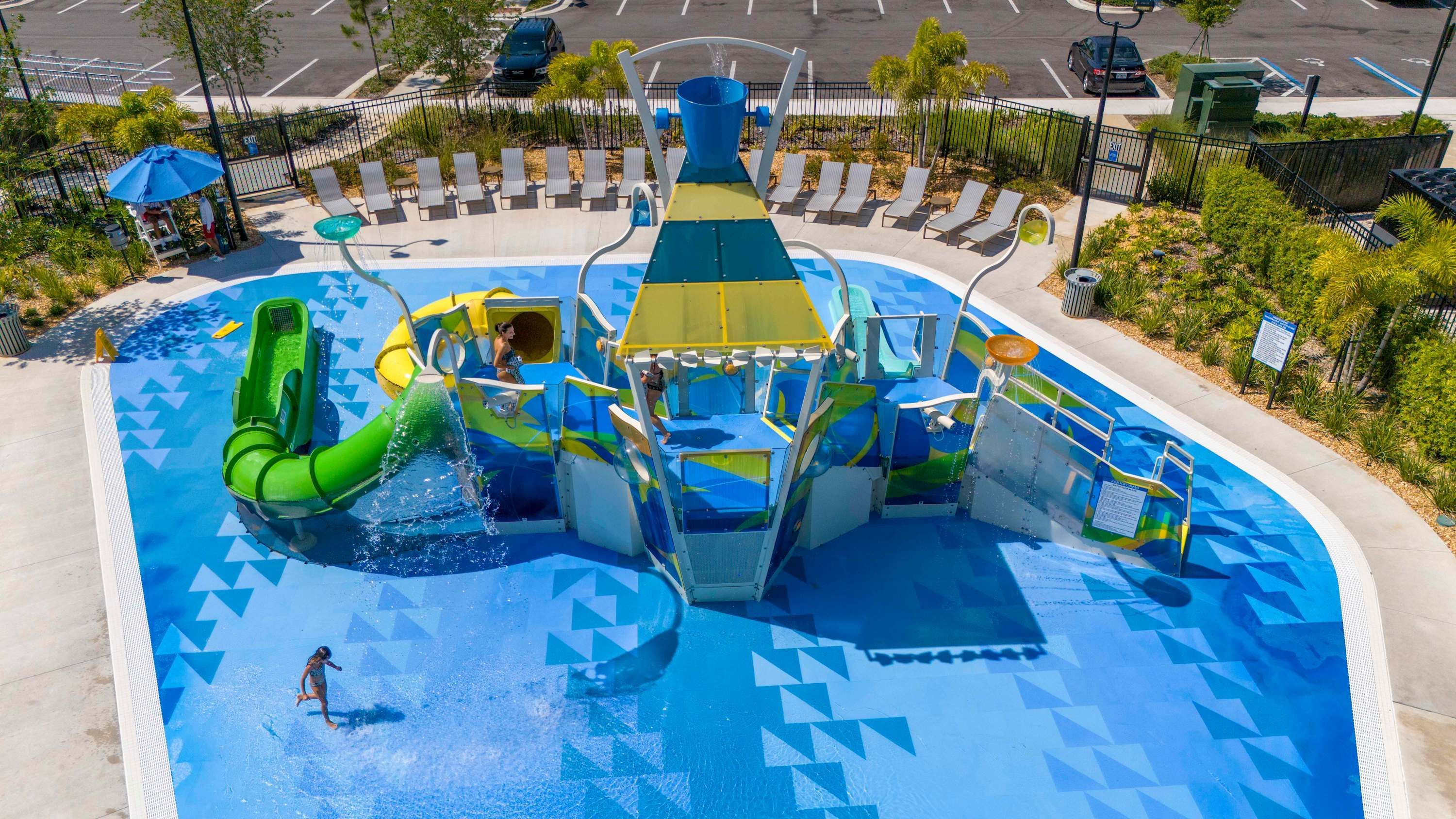 Een waterpark met een groot zwembad, glijbanen en een speelstructuur.