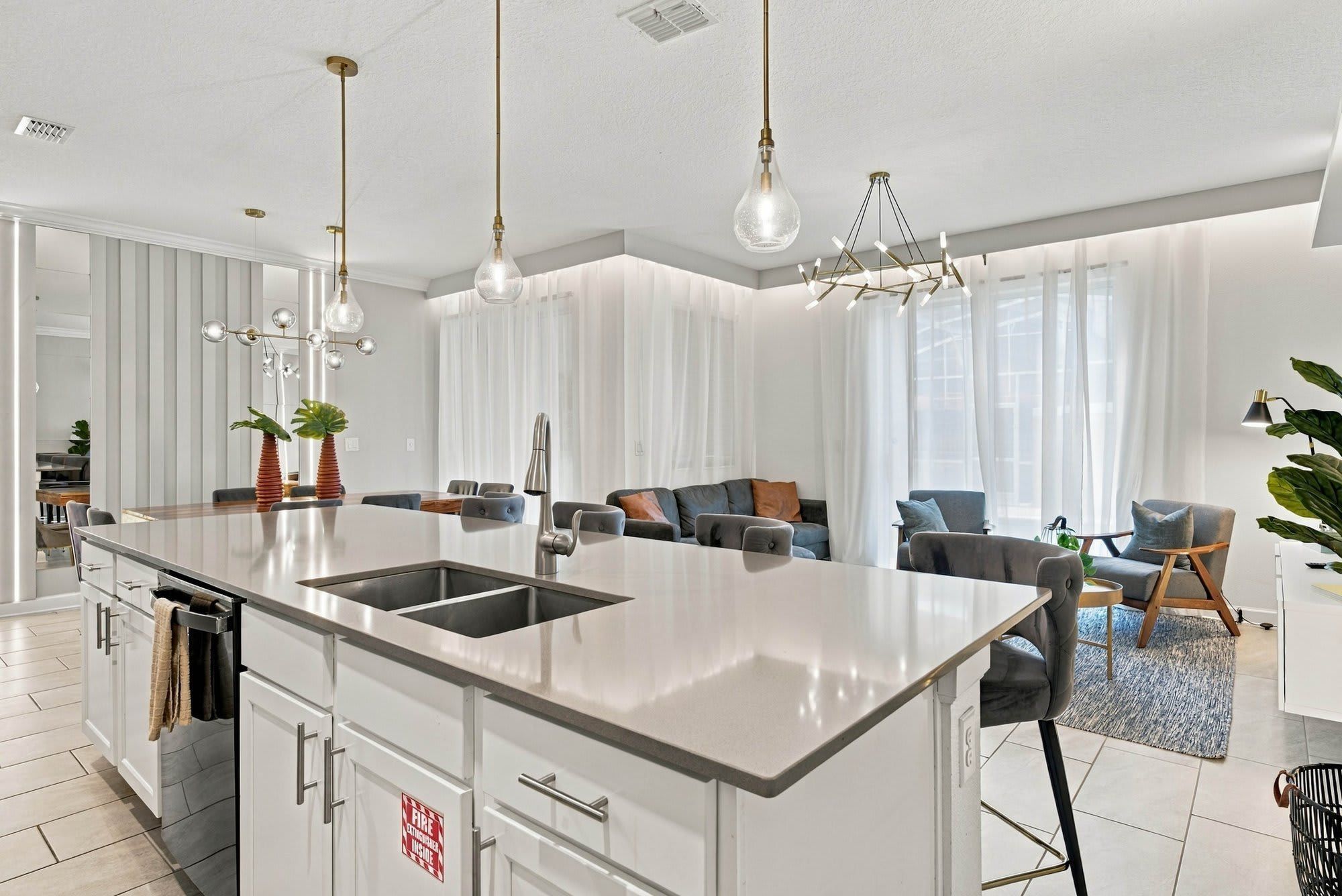 Een moderne keuken met een centraal eiland, roestvrijstalen apparatuur en hanglampen.