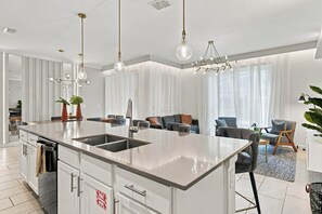 Een moderne keuken met een centraal eiland, roestvrijstalen apparatuur en hanglampen.