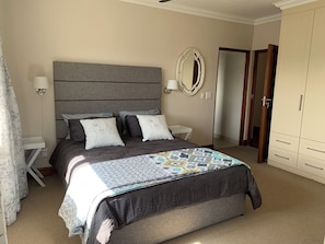 Une chambre à coucher avec un lit, des tables de chevet, un miroir et une armoire.