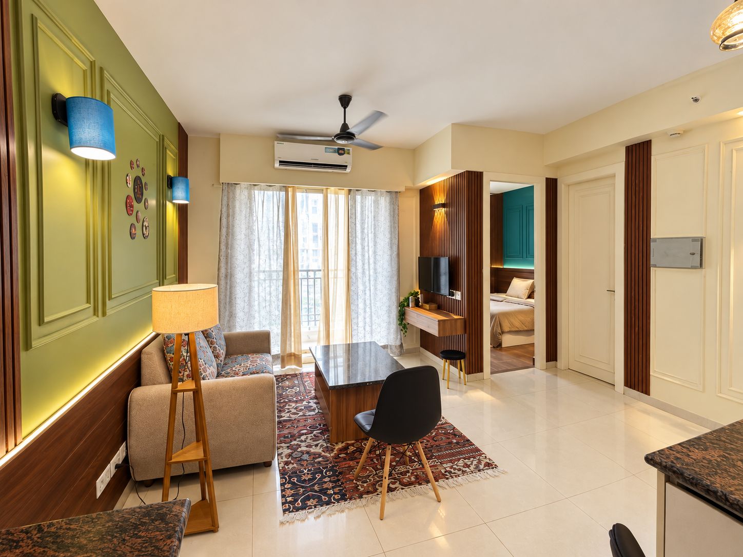 Una habitación de hotel moderna con zona de comedor, sofá, televisor y cama.